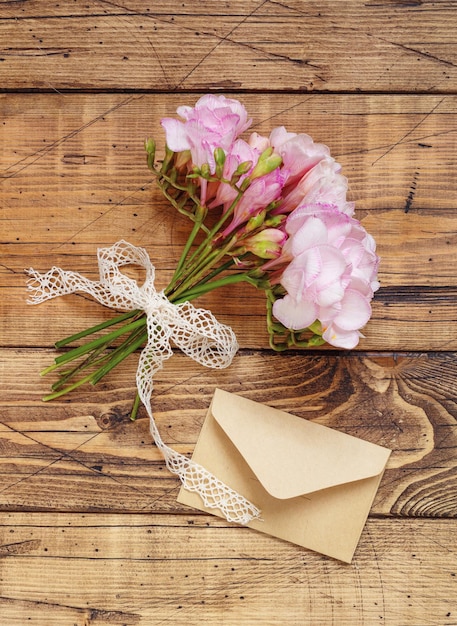 Blumenstrauß aus schönen Freesienblumen mit Band- und Umschlagdraufsicht. Modell auf Holztisch. Rosa Blumen für Feiertagsfeiern, flach. Geburtstag, Muttertag, Valentinstag Konzept
