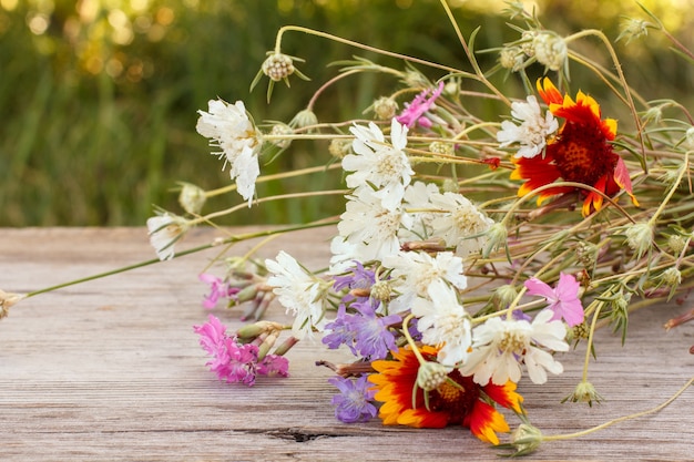 Foto blumenstrauß aus wildblumen auf altem holzbrett mit natürlichem hintergrund.