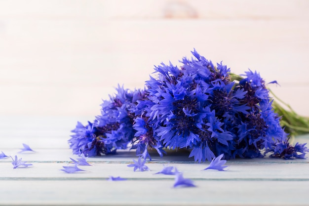 Blumenstrauß der frischen Kornblumen auf einem hellen hölzernen Tischhintergrund