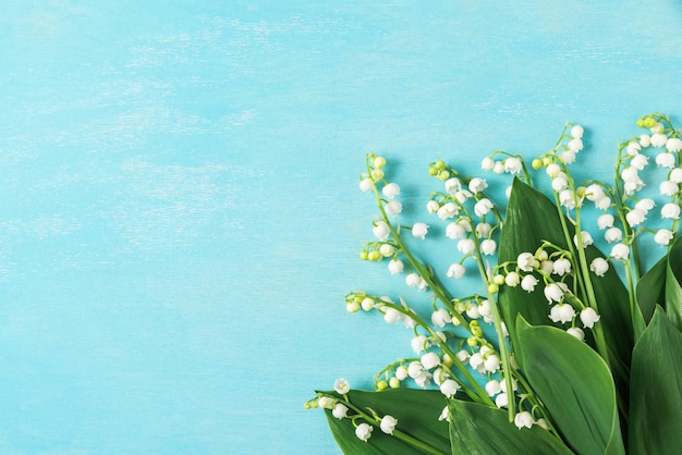 Blumenstrauß der Frühlingsblumen Maiglöckchen auf blauem Holzhintergrund. Draufsicht mit Kopierraum. flach liegen