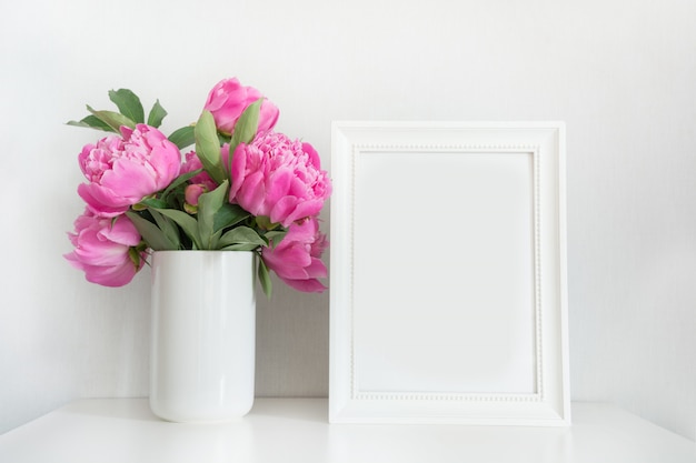 Blumenstrauß der rosa Pfingstrose im Vase mit Fotorahmen für Text auf Weiß. Muttertag.