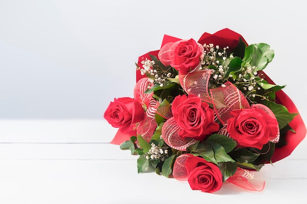 Blumenstrauß der roten Rosen über weißem Holztisch Women39s Tageshintergrund