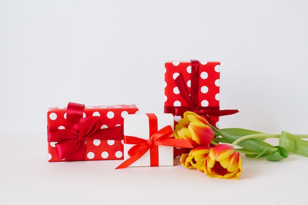 Blumenstrauß der schönen Frühlingstulpen in der Vase und in der Geschenkbox auf Tisch gegen hellen Hintergrund. Valentinstag