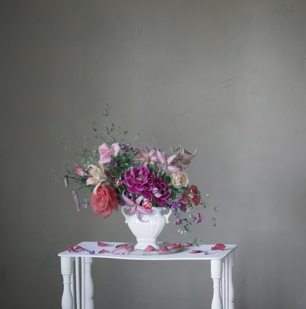 Blumenstrauß der Sommerblumen in der Vase auf Weinleseweißholzregal