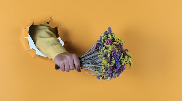 Blumenstrauß in der Hand auf gelbem Papierhintergrund