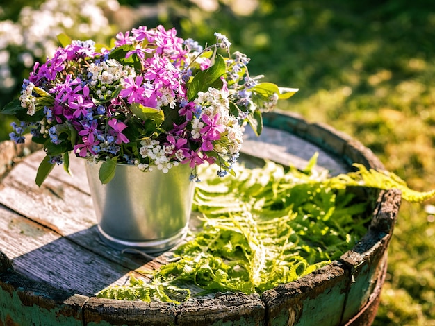 Foto blumenstrauß in zinntöpfen auf einem alten holzfass.