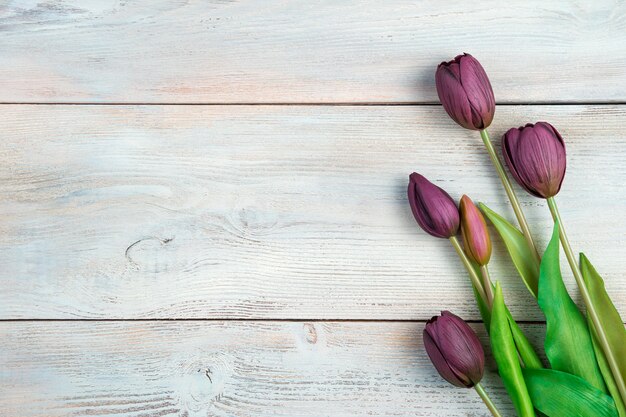 Blumenstrauß mit Tulpen auf einem hellen hölzernen Hintergrund.