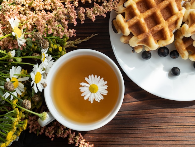 Blumenstrauß, Nachtisch auf einer weißen Platte, eine Tasse Tee