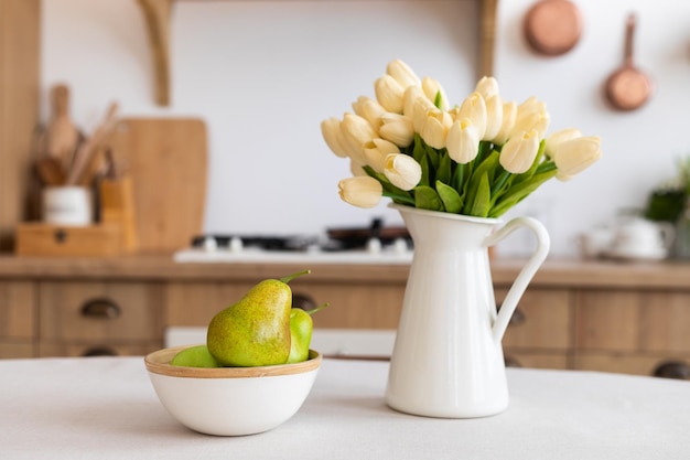 Foto blumenstrauß und eine schüssel mit birnen auf dem küchentisch