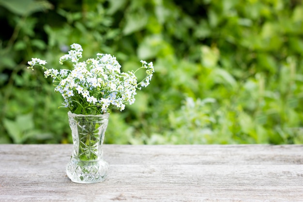 Blumenstrauß von blauen Blumen in einer Vase auf einem hölzernen Hintergrund, natürlicher Hintergrund