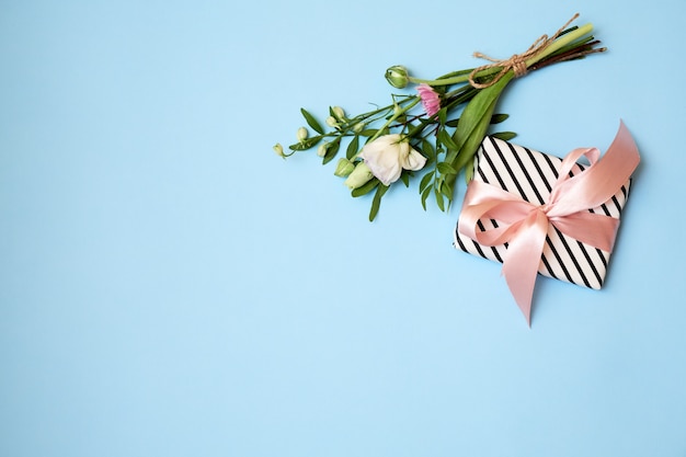 Blumenstrauß von Blumen, Geschenkbox, Band auf blauem Hintergrund mit Kopienraum