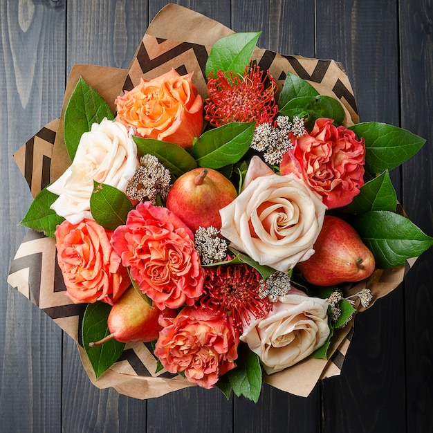 Blumenstrauß von Blumen mit Birnen auf einem dunklen hölzernen Hintergrund. Fruchtstrauß