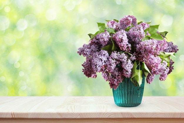 Blumenstrauß von Fliedern auf einem Holztisch. Blumen in einem Vase auf unscharfem Frühlingshintergrund mit bokeh.