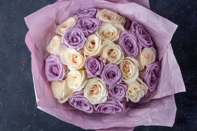 Blumenstrauß von frischen erstaunlichen weißen und lila Rosen in Bastelpapier