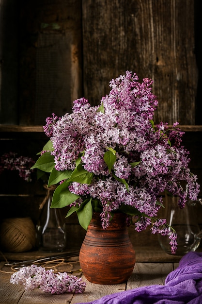 Blumenstrauß von lila Blumen in einem keramischen Topf auf alter Tabelle