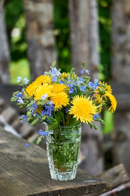 Blumenstrauß von Löwenzahn- und Veronica-Blumen in einem Glas