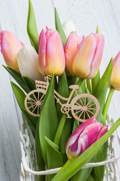 Blumenstrauß von rosa gelben Tulpen und von hölzernem Fahrrad