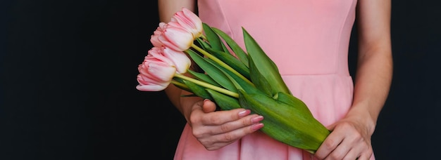 Blumenstrauß von rosa Tulpen in den Händen der Frauen