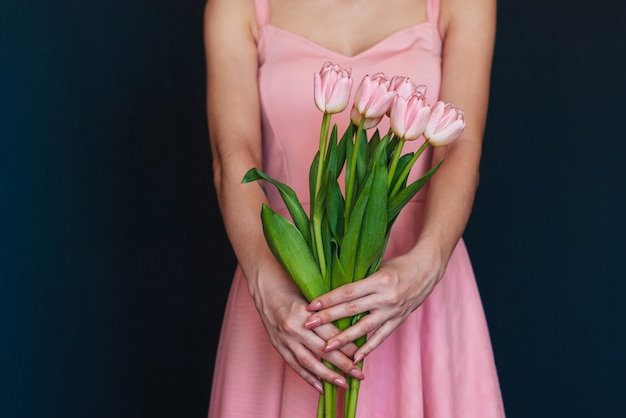 Blumenstrauß von rosa Tulpen in den Händen eines Mädchens