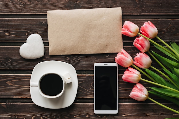 Blumenstrauß von rosa Tulpenblumen mit einem Tasse Kaffee und einem Smartphone zum Morgenfrühstück