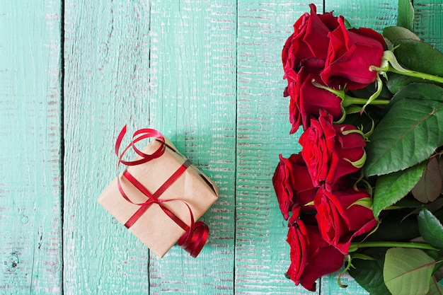 Blumenstrauß von roten Rosen auf einem Holztisch.