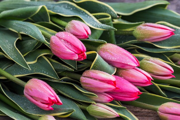 Blumenstrauß von Tulpen mit Wasser fällt auf Tabelle. Nahansicht.