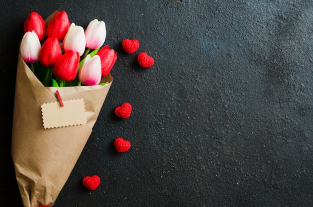 Blumenstrauß von Tulpen und von Geschenkbox auf dunklem Hintergrund.