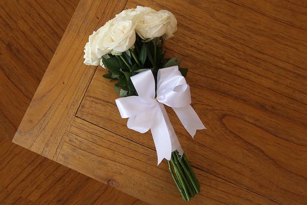 Blumenstrauß von weißen Rosen in einem Holztisch