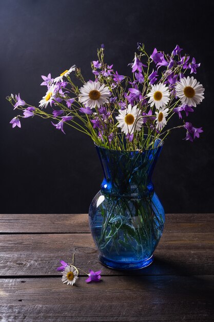 Blumenstrauß von Wildblumen aus Kamille, Gänseblümchen und Glockenblumen auf einem alten hölzernen Hintergrund