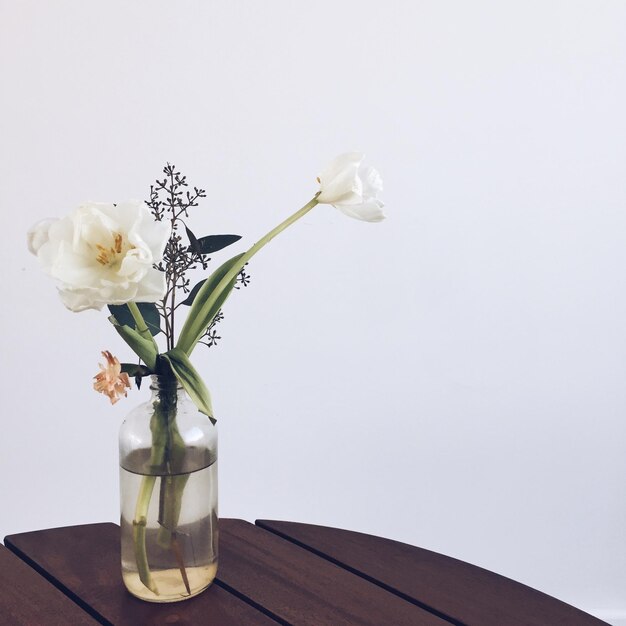Blumenvase auf Tisch vor weißem Hintergrund
