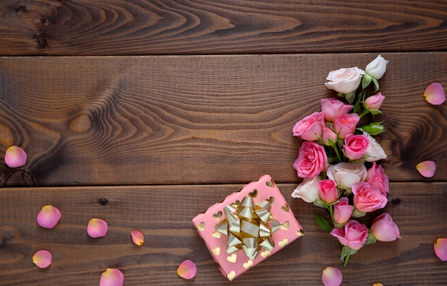 Blumenzusammensetzung mit einem Kranz von rosa Rosen auf hölzernem Hintergrund. Valentinstag Hintergrund.