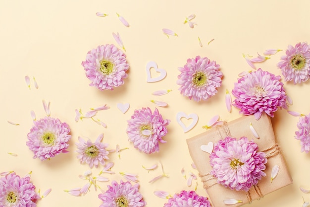 Blumenzusammensetzung mit Herzen und Geschenkbox auf einem pastellgelben Hintergrund