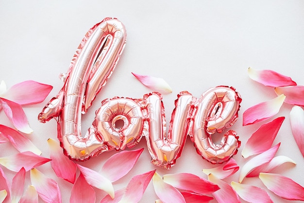 Blumige Blütenblätter und das Wort Liebe aus dem kreativen Layout des Folienballons