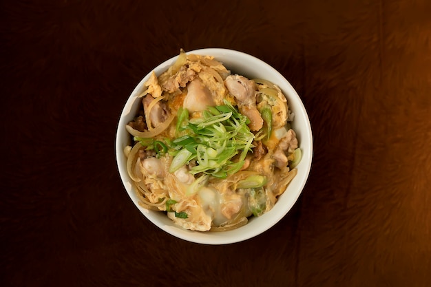 Blurry Tasty Oyakodon, japanisches Reisschüsselgericht, garniert mit Hühnchen, Ei, geschnittener Frühlingszwiebel