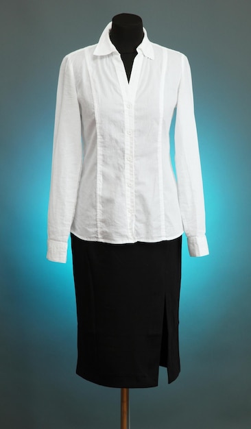 Blusa blanca y falda negra con abrigo en maniquí sobre fondo de color