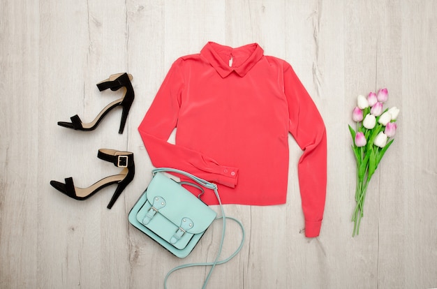Blusa coral, zapatos negros, bolso, ramo de tulipanes. Concepto de moda