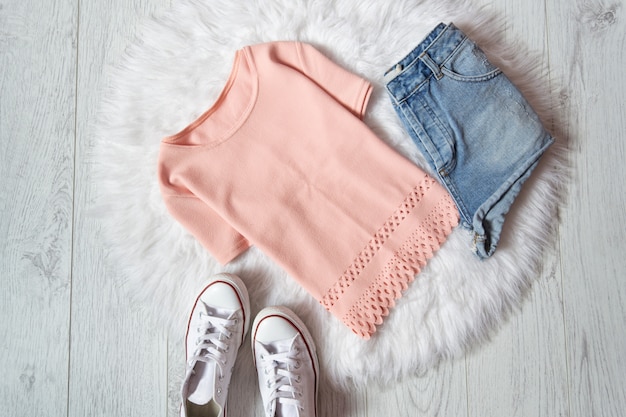 Blusa rosa, shorts jeans e tênis em pêlo branco