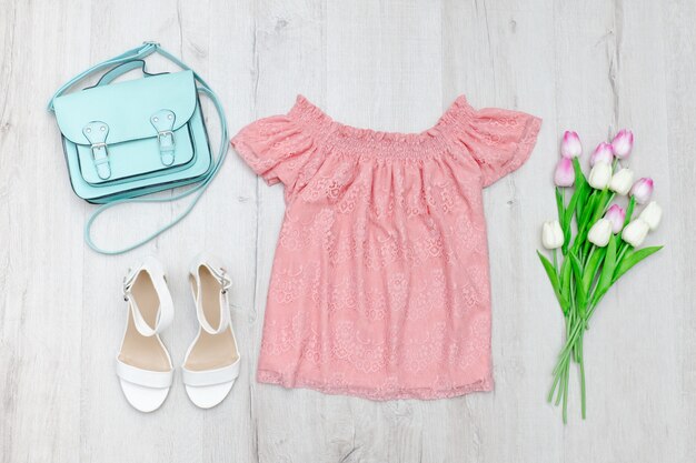 Blusa rosa, zapatos blancos, bolso y un ramo de tulipanes.