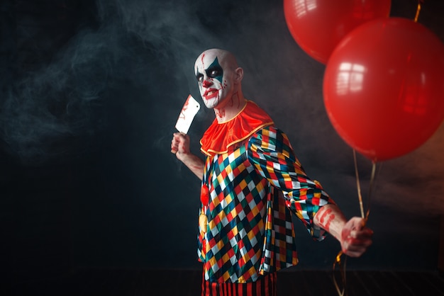 Blutiger Clown mit Hackmesser hält Luftballon