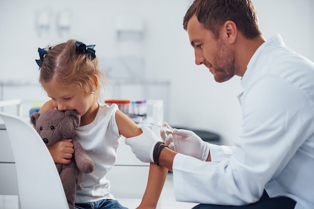 Foto blutprobe. kleines mädchen ist mit arzt in der klinik.