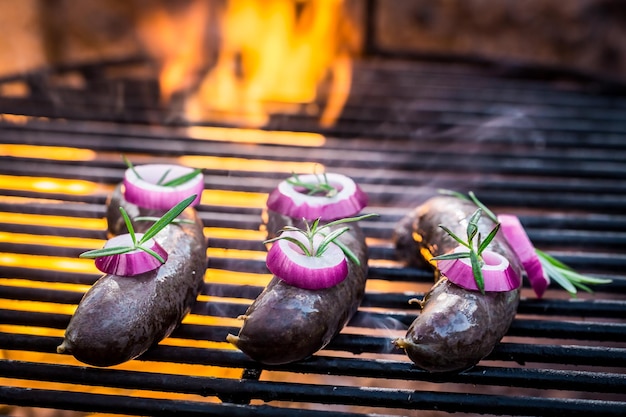 Blutwurst mit Zwiebeln auf dem Grill und Feuer