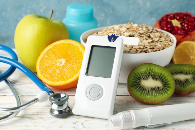 Blutzuckermessgerät und diabetisches Essen auf Holztisch