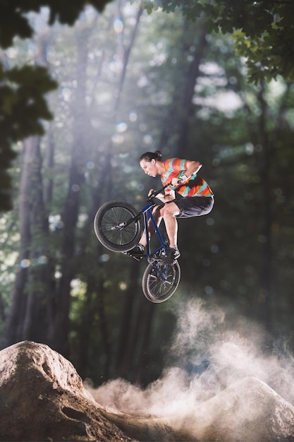 Bmx-Fahrradfahrer, der auf den Waldhügeln austrickst