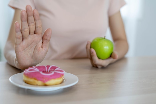Foto boa alimentação e dieta saudável as mulheres rejeitam junk food ou alimentos não saudáveis, como rosquinhas, e escolhem alimentos saudáveis, como maçã verde