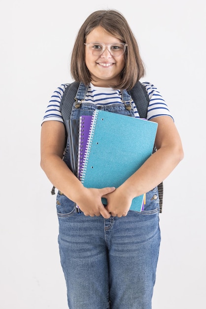 Boa aluna modesta usa óculos e segura seus materiais de estudo nas mãos sorrindo