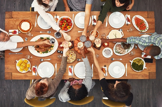 Boa comida é ainda melhor com bons amigos Foto de um grupo de pessoas sentadas juntas em uma mesa de jantar prontas para comer