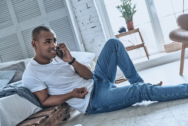 Boa conversa com a namorada. Africano jovem bonito falando ao telefone e sorrindo