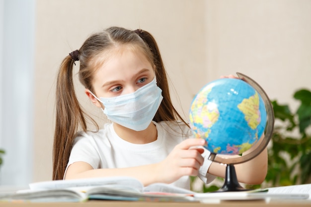 Boa menina da escola vendo o globo em casa durante a quarentena