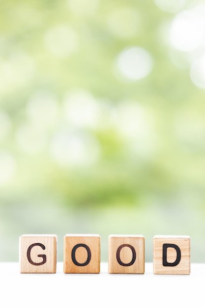 BOA palavra está escrita em cubos de madeira em um fundo verde de verão Closeup de elementos de madeira