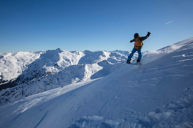 Boarder em um snowboard pulando em um lindo dia no inverno de grandes montanhas nos Alpes